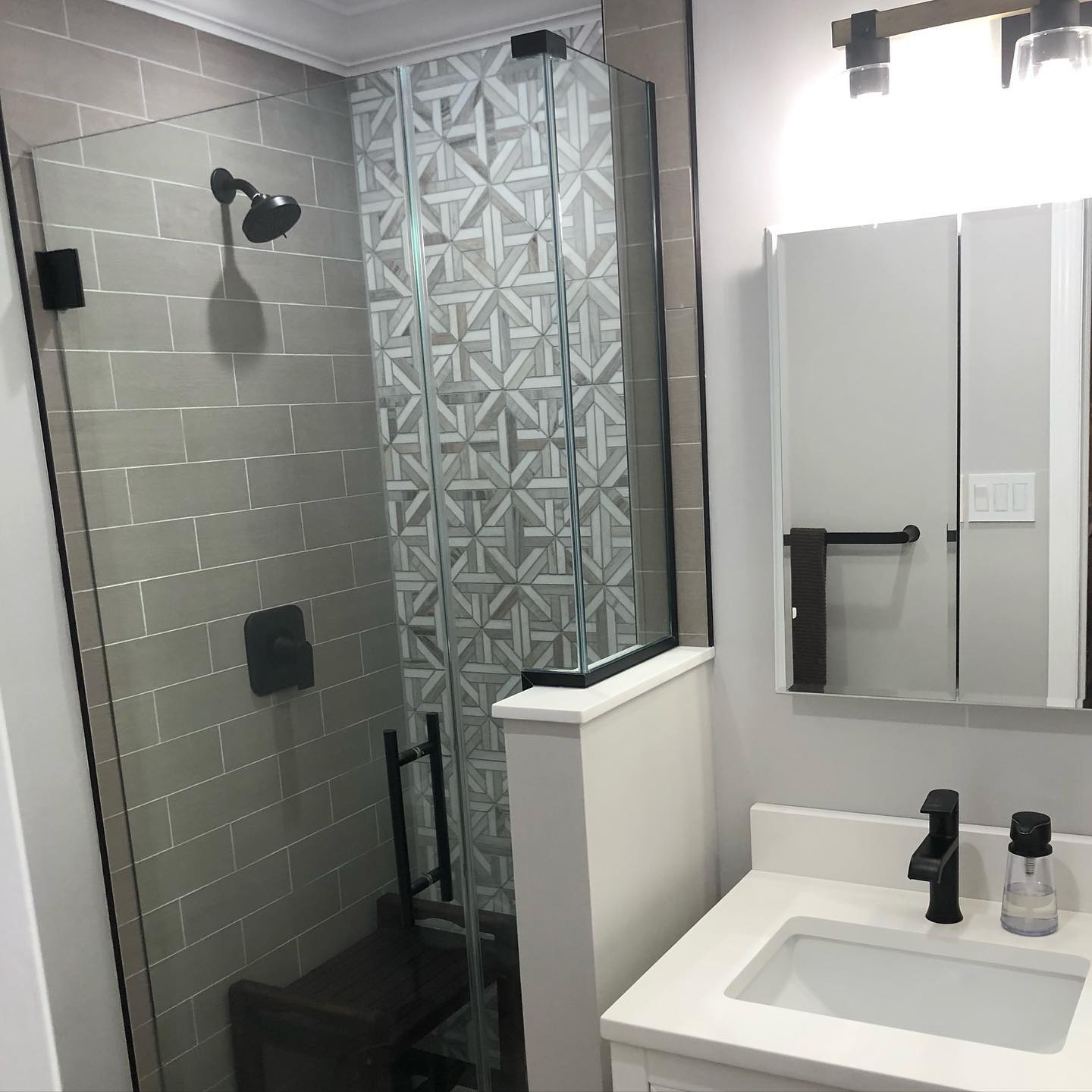 Full bathroom renovation in Syosset NY. #BathroomRemodel #PalissandroMarbleMosiac #CustomShowerDoor #WhiteQuartzCounterTop #WhiteShakerVanity #BlackFixtures #WoodTiles